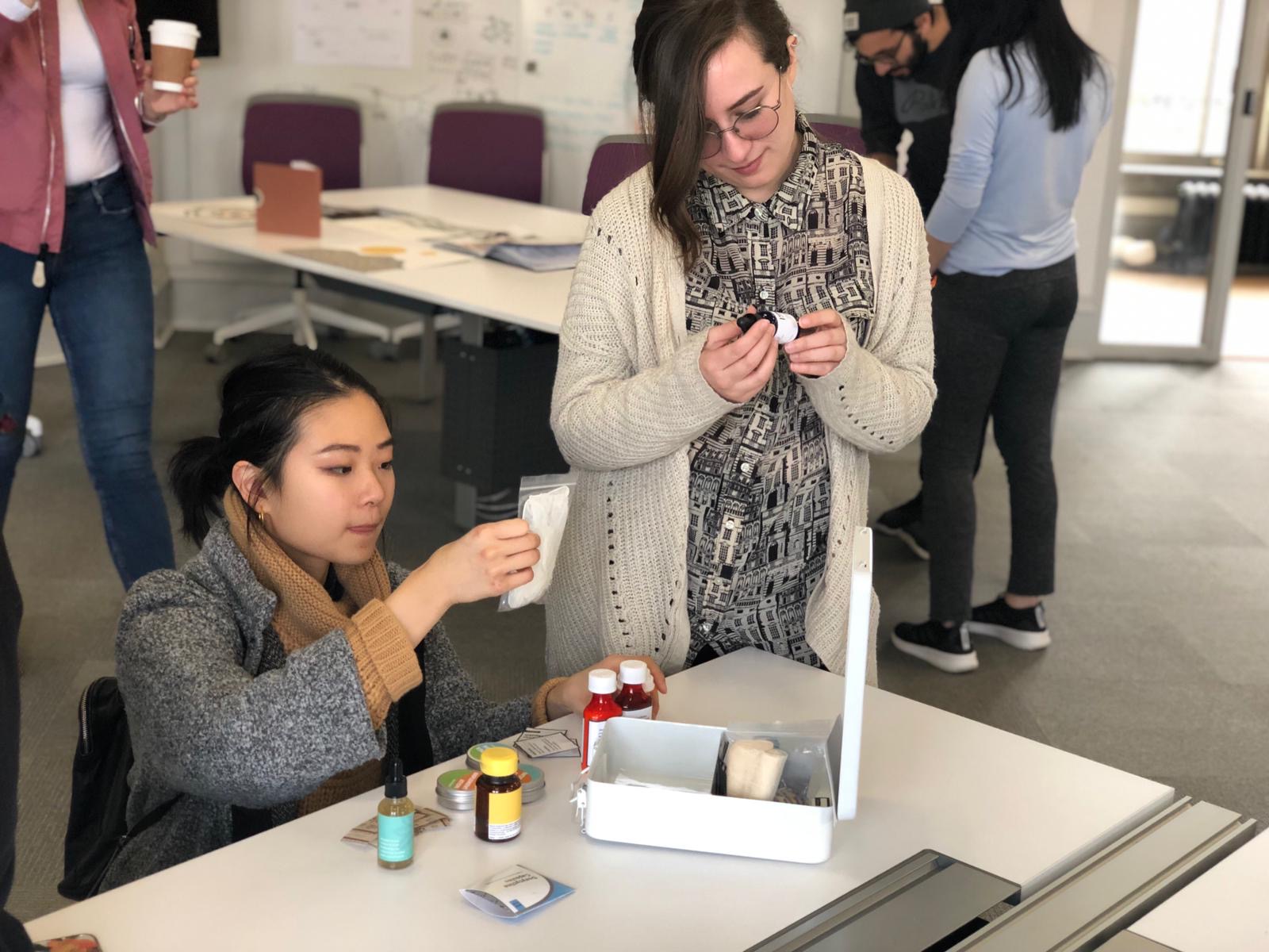 Two women looking at the contents of a first aid kit.