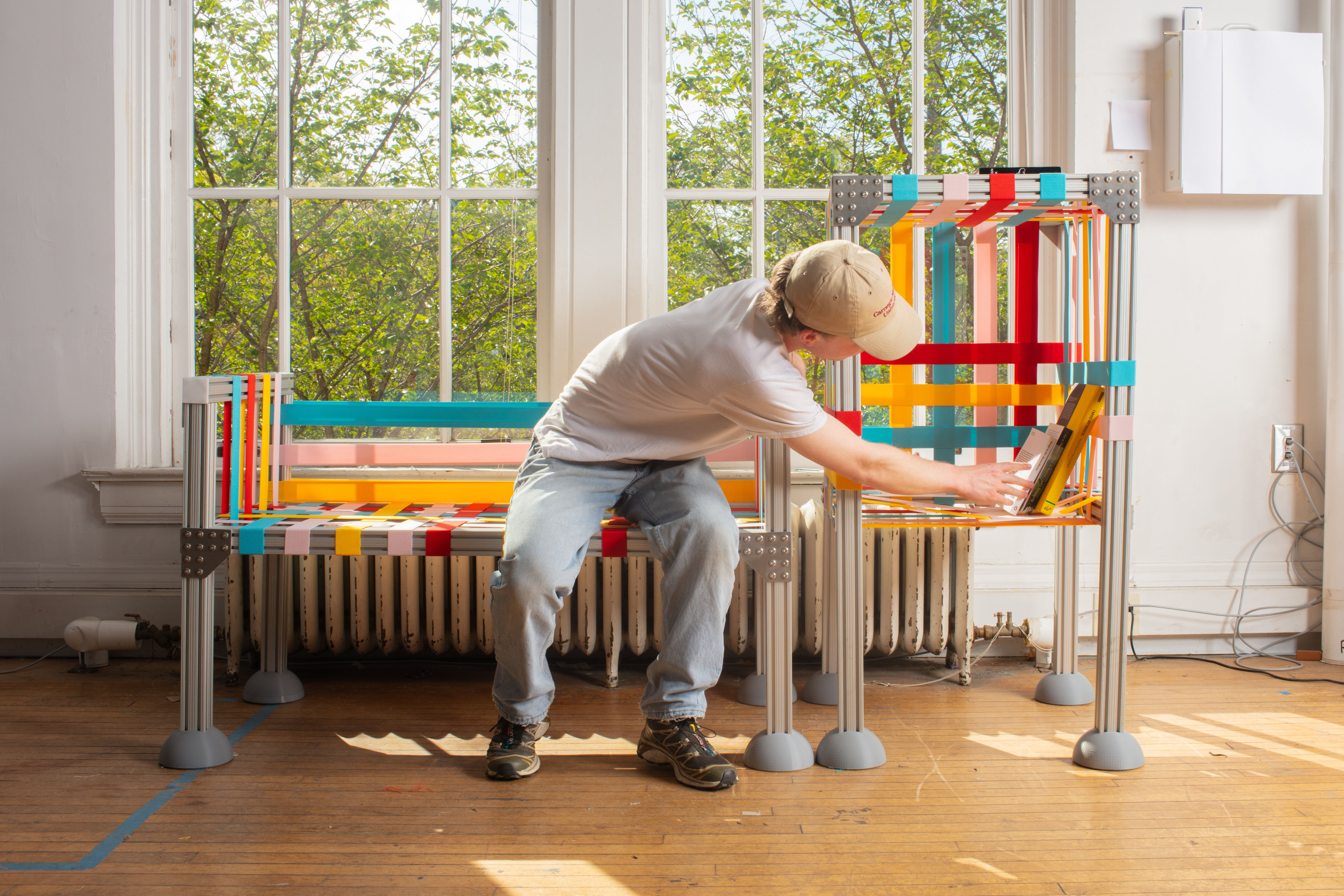 A man sitting on a colorful bench and interacting with a colorful shelf