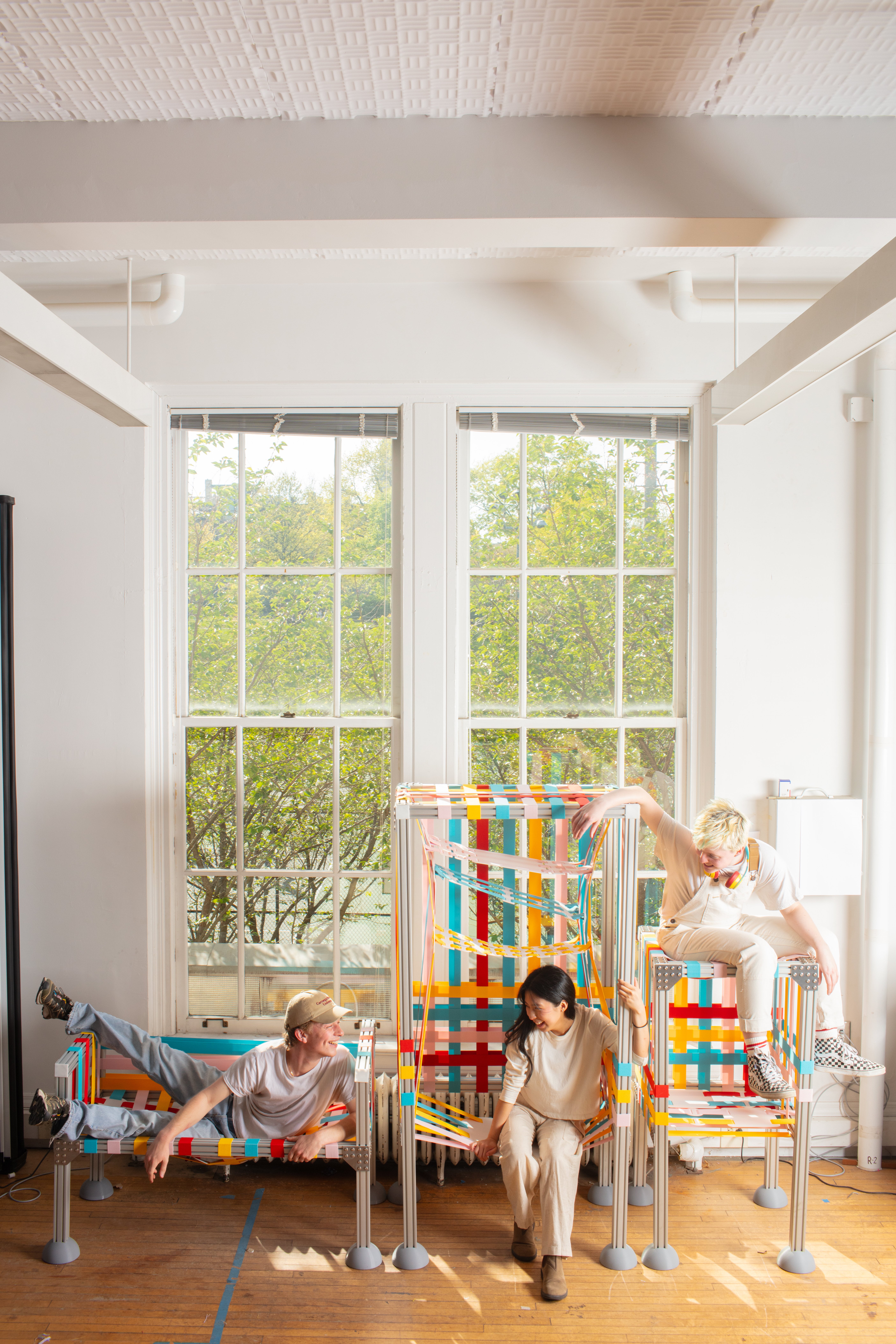 3 people sitting on 3 pieces of colorful furniture
