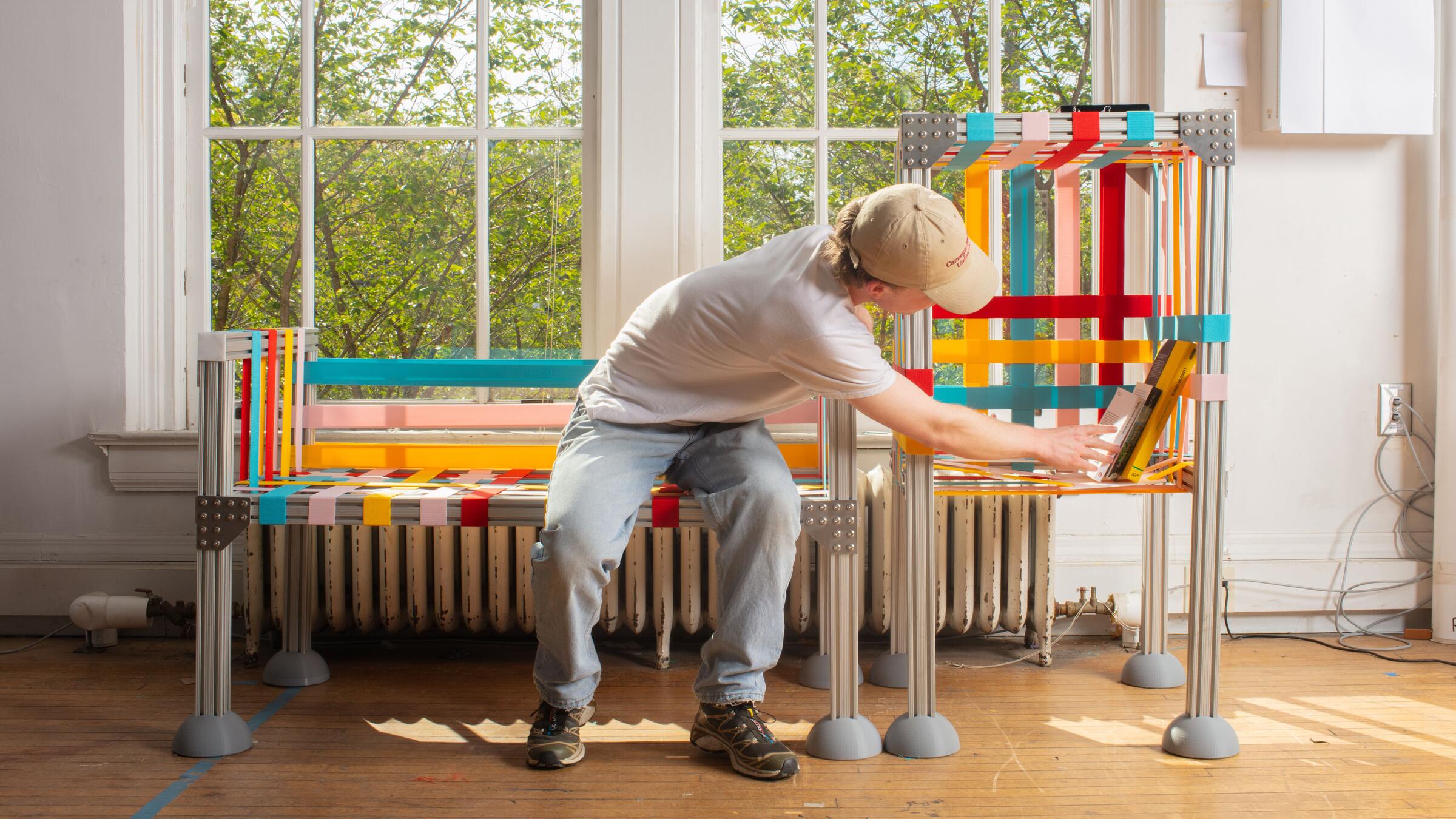 A man sitting on a colorful bench and interacting with a colorful shelf