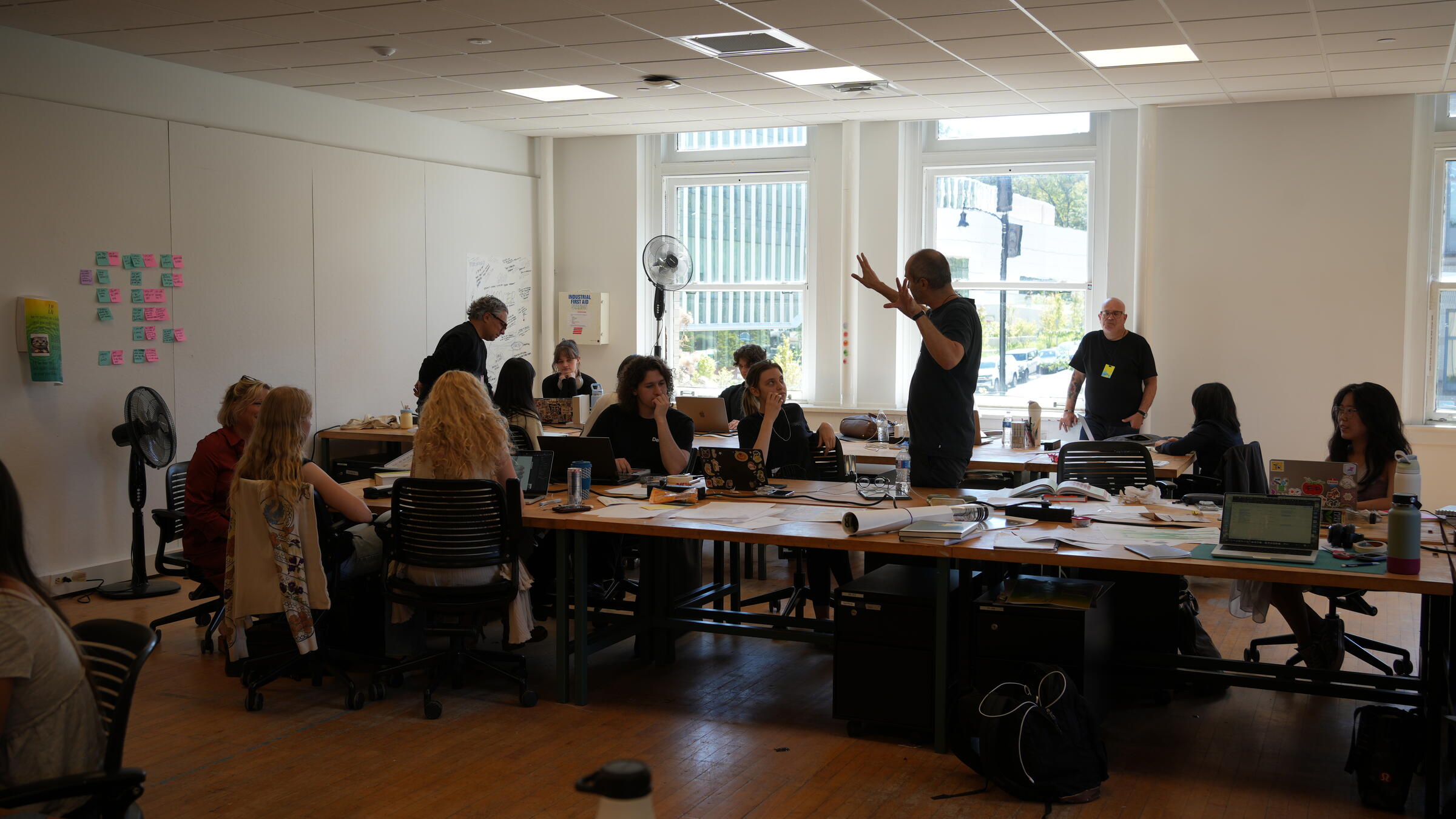 A man talking to a studio full of students