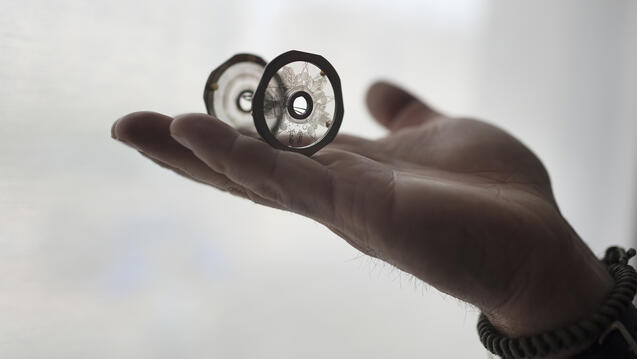 A hand holding the inner discs of the MoonArk's Earth Chamber