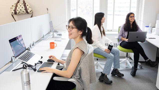 Three Master's Students working at their studio desks