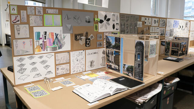 A desk in a studio filled with student work
