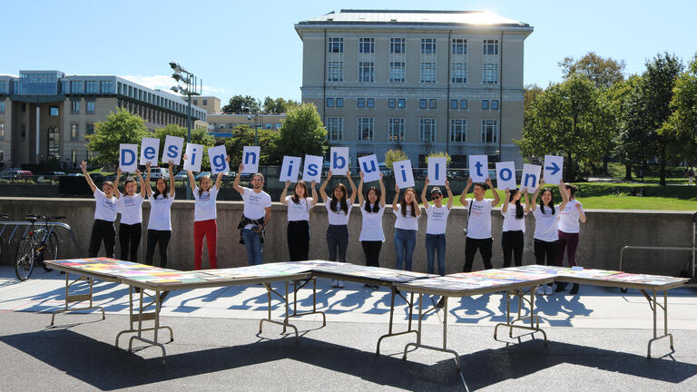 A group of Design students holding up letters that spell out "Design is Built ON"