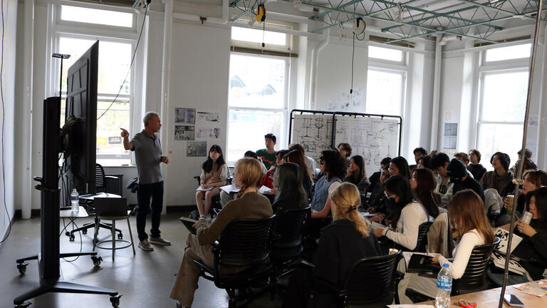 Dan Boyarski pointing to a screen to a studio full of students