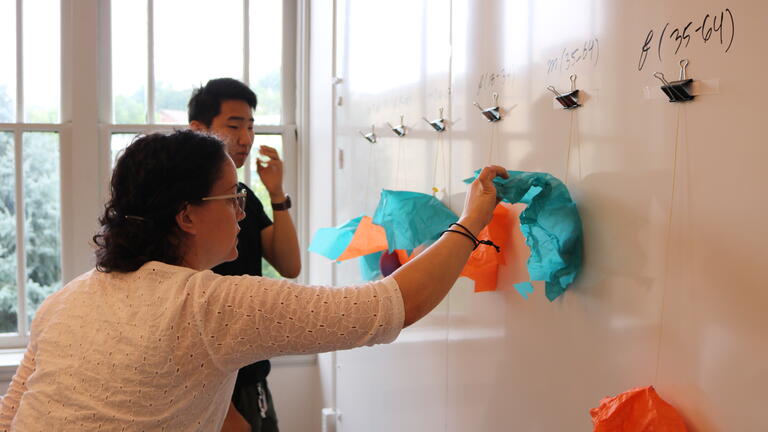 Master's students hanging paper on a whiteboard