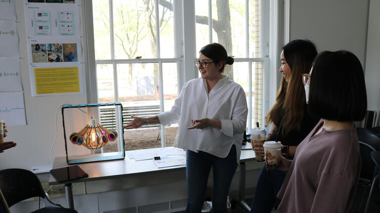 A Master's Student displaying a prototype light fixture