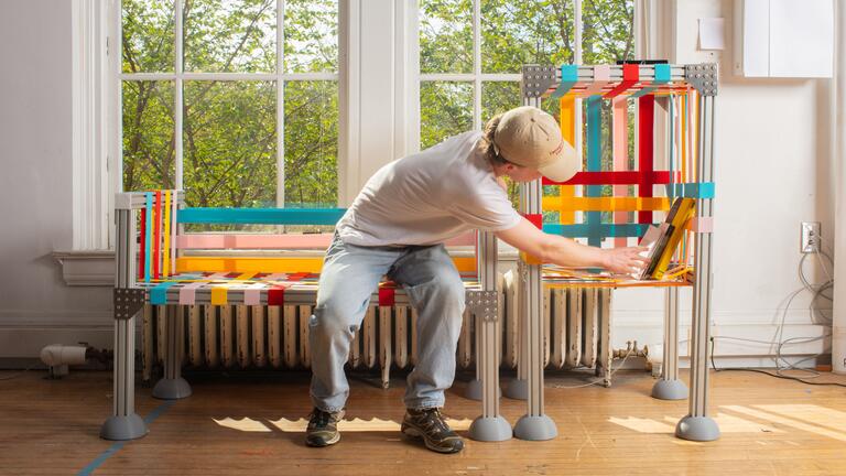 A man sitting on a colorful bench and interacting with a colorful shelf