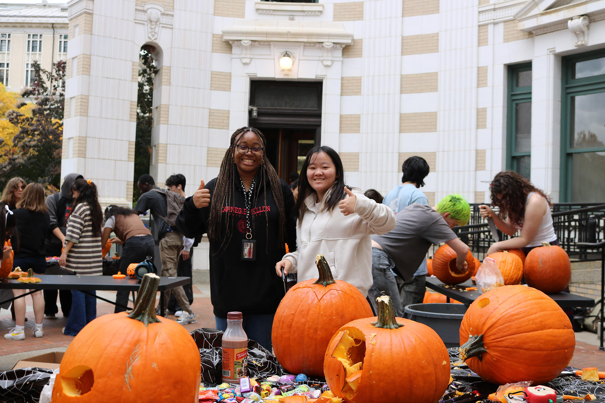 Students giving a thumbs up at a pumpkin carving event.